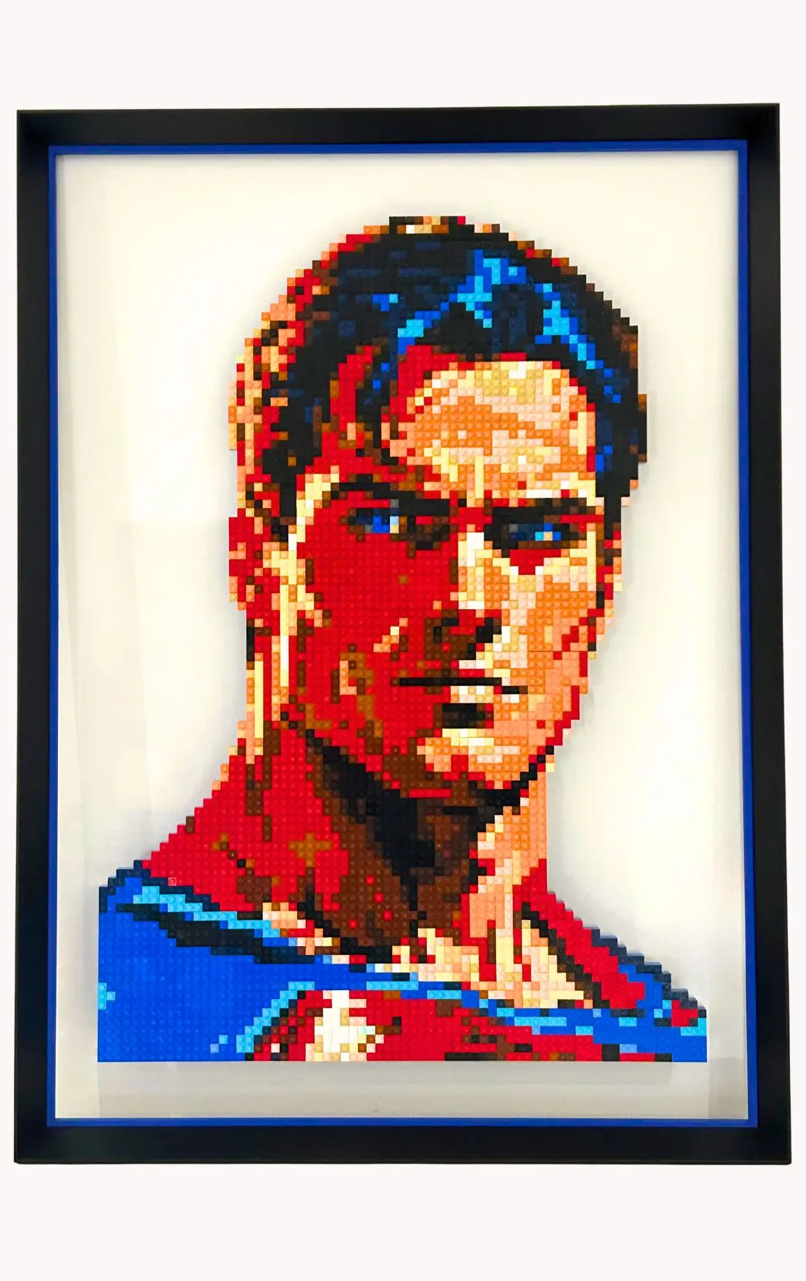 Portrait de Superman réalisé en briques LEGO®, monté sur plexiglas et encadré dans un cadre Nielsen en aluminium noir mat avec réhausse bleue, œuvre de l’artiste qargo.