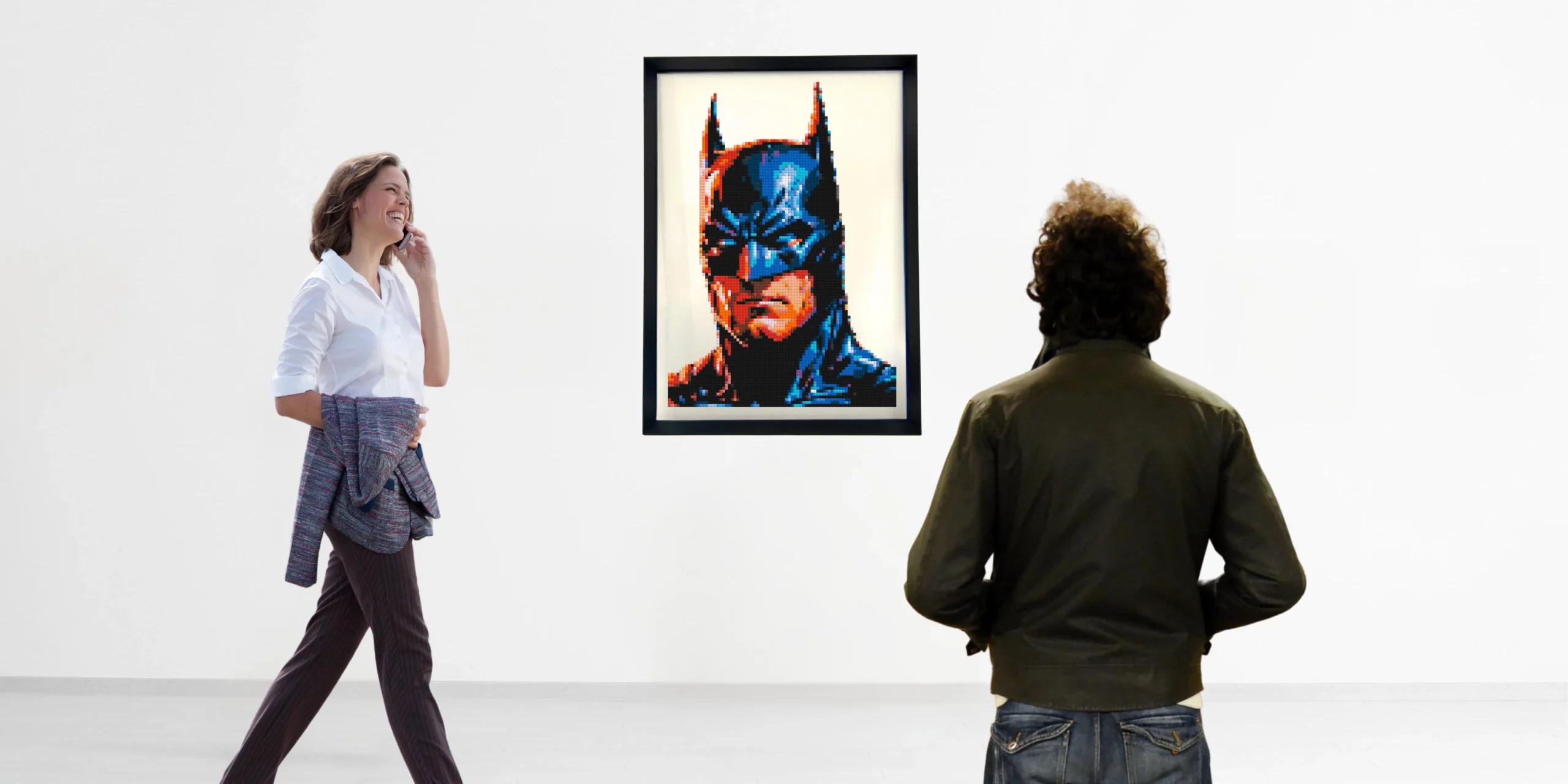 Œuvre Batman en briques LEGO® par l’artiste qargo exposée au mur, observée par des visiteurs dans un espace d’exposition